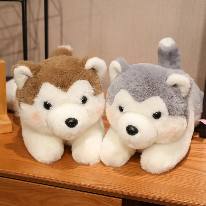 Two plush husky kawaii toys, one brown and white, the other gray and white, on a wooden surface.