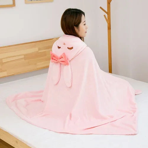 Person wrapped in a pink kawaii hooded blanket with a bow on a bed.