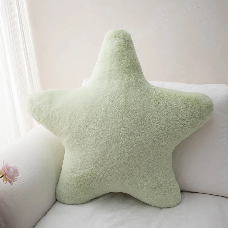 Green star-shaped kawaii pillow on a white couch with a light background