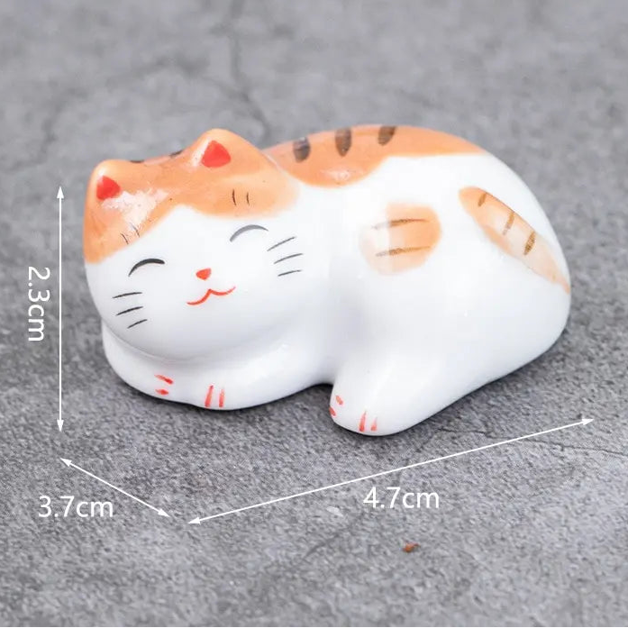 Small ceramic kawaii cat figurine with dimensions on a gray surface