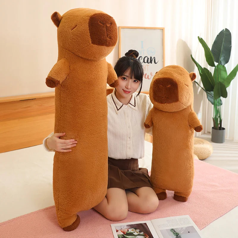 Woman holding two large kawaii brown teddy bears in a room with a plant and framed picture on the wall.