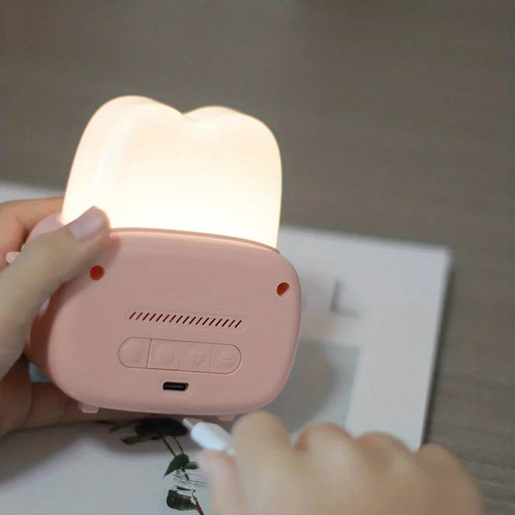 Pink kawaii night light with a soft glow held by a hand against a neutral background
