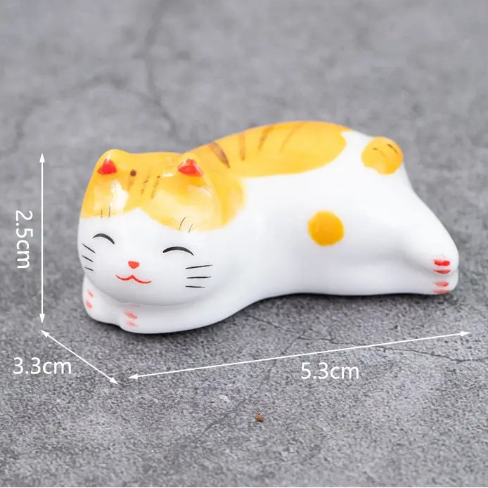 Small ceramic kawaii cat figurine with measurements on a gray background