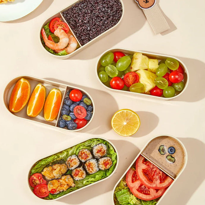 Children's kawaii lunchbox with compartments filled with various food items on a white background