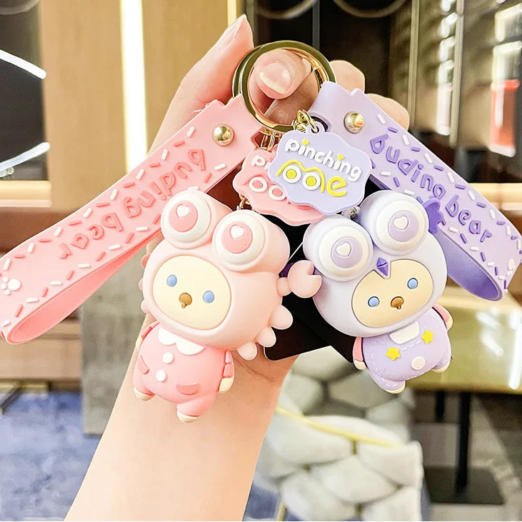 Two cute keychains shaped like kawaii bunnies held by a hand with a blurred background.
