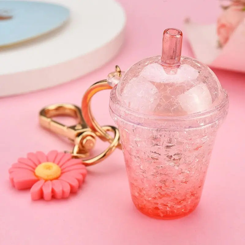 Pink glittery cup kawaii keychain with a flower charm on a pink background
