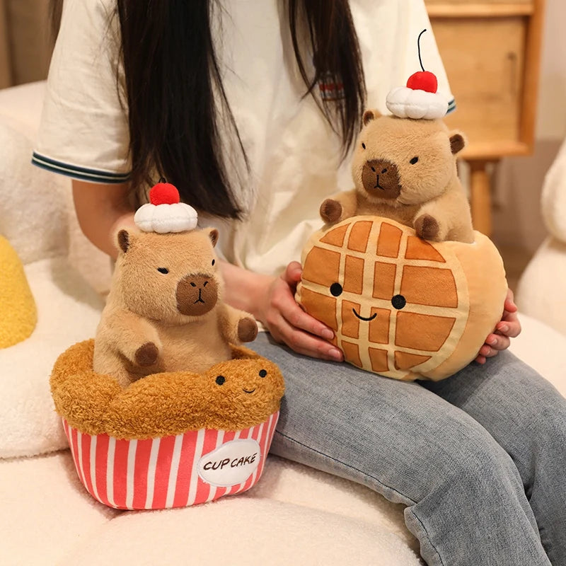 Person holding kawaii plush toys shaped like a waffle, cupcake, and bear on a soft surface.