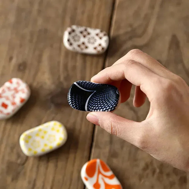 Hand holding a kawaii patterned rock on a wooden surface with other rocks in the background
