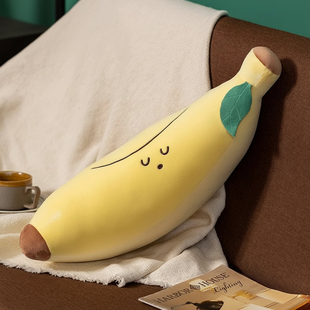 Kawaii plush banana pillow on a couch with a cup and magazine in the background