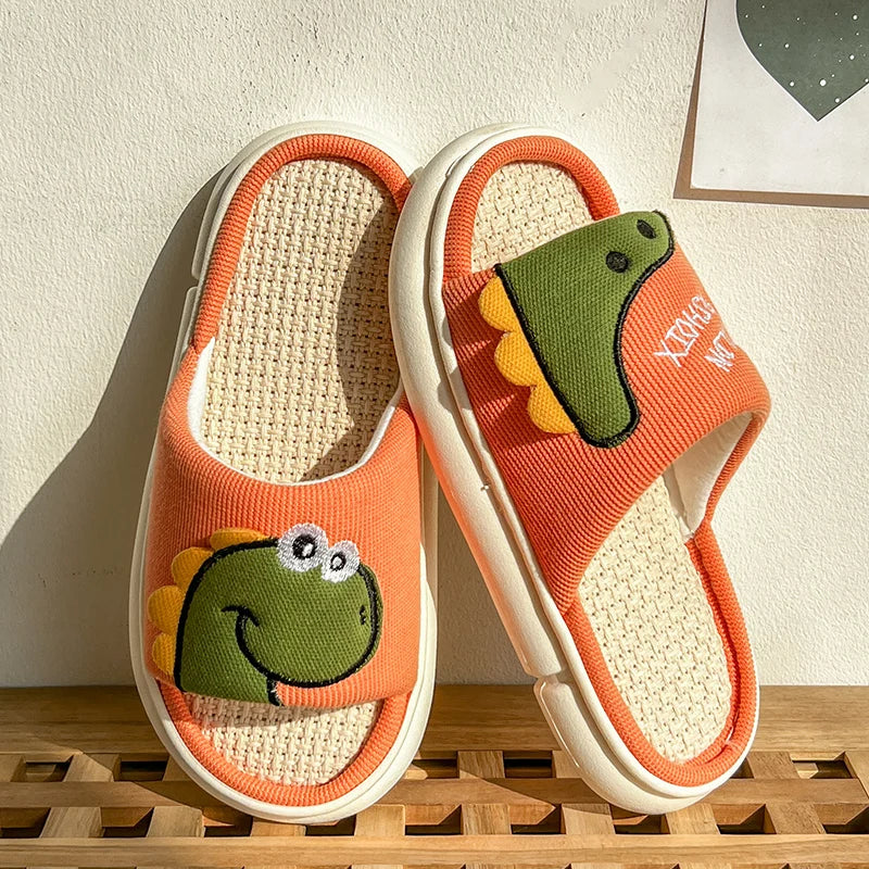 Pair of orange slippers with frog kawaii design on a wooden surface.