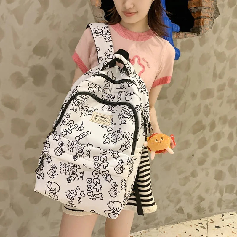 Person wearing a white backpack with black patterns, holding a small Kawaii plush toy, against a textured wall.