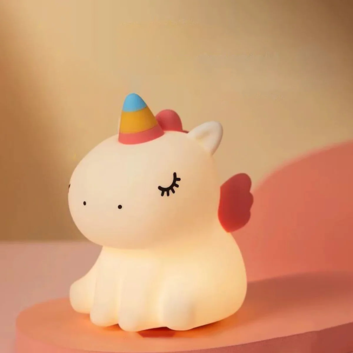 Unicorn-shaped kawaii night light with a rainbow horn and pink bow on a warm background