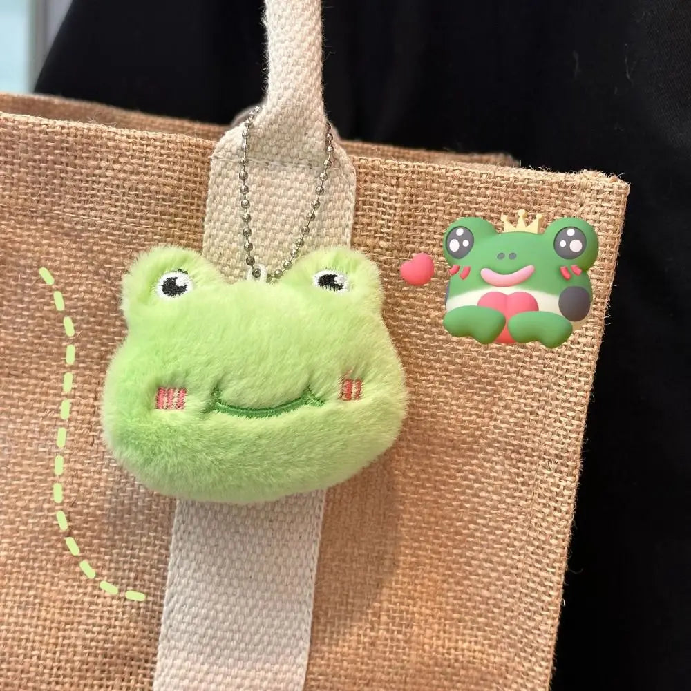 Green kawaii frog-shaped keychain attached to a brown bag with a cartoon frog illustration.