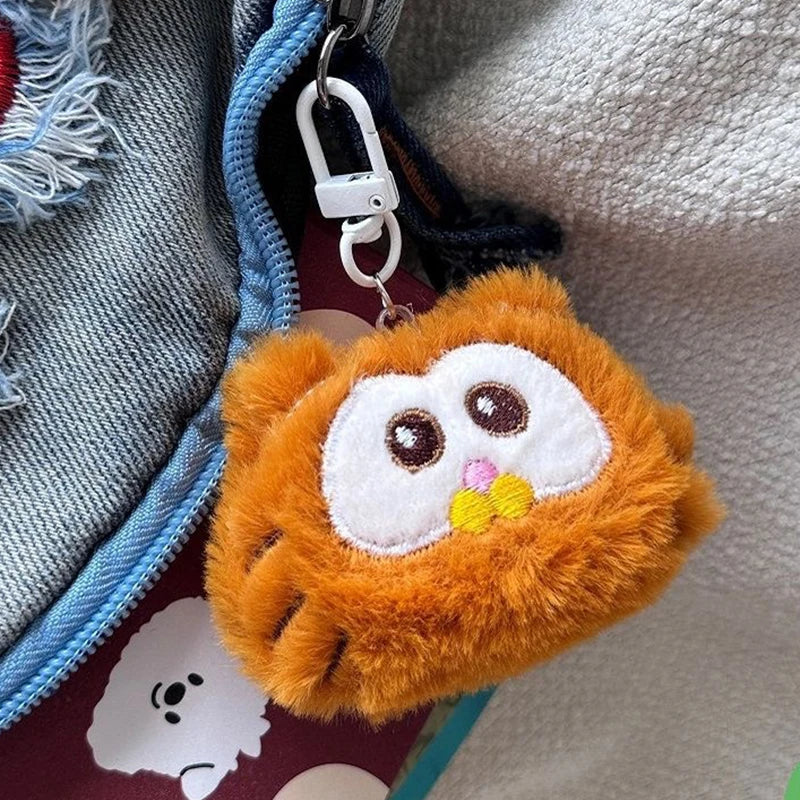 Fluffy kawaii orange keychain with a face on a textured surface