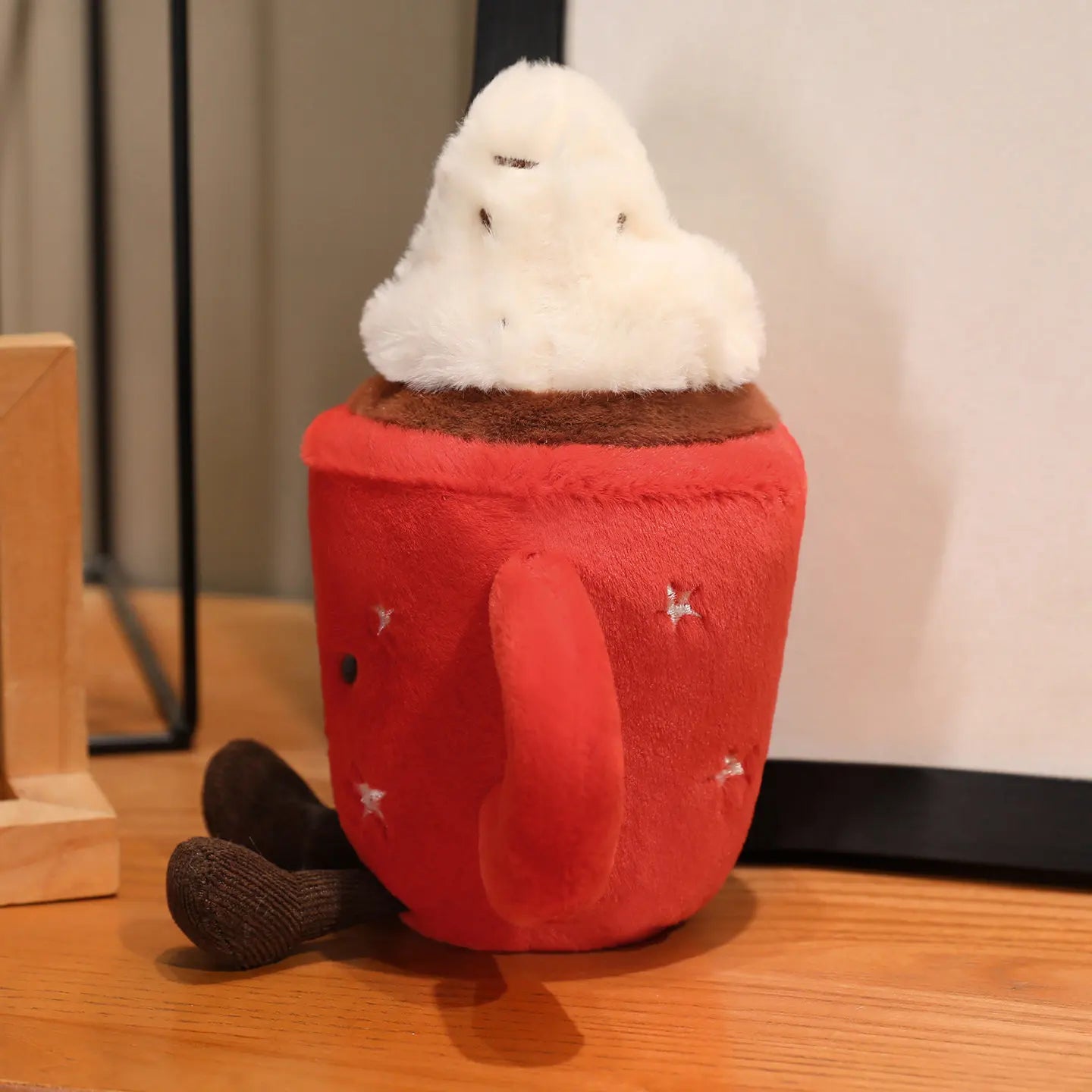 Plush kawaii toy shaped like a red cup with a white cloud on top, sitting on a wooden surface.