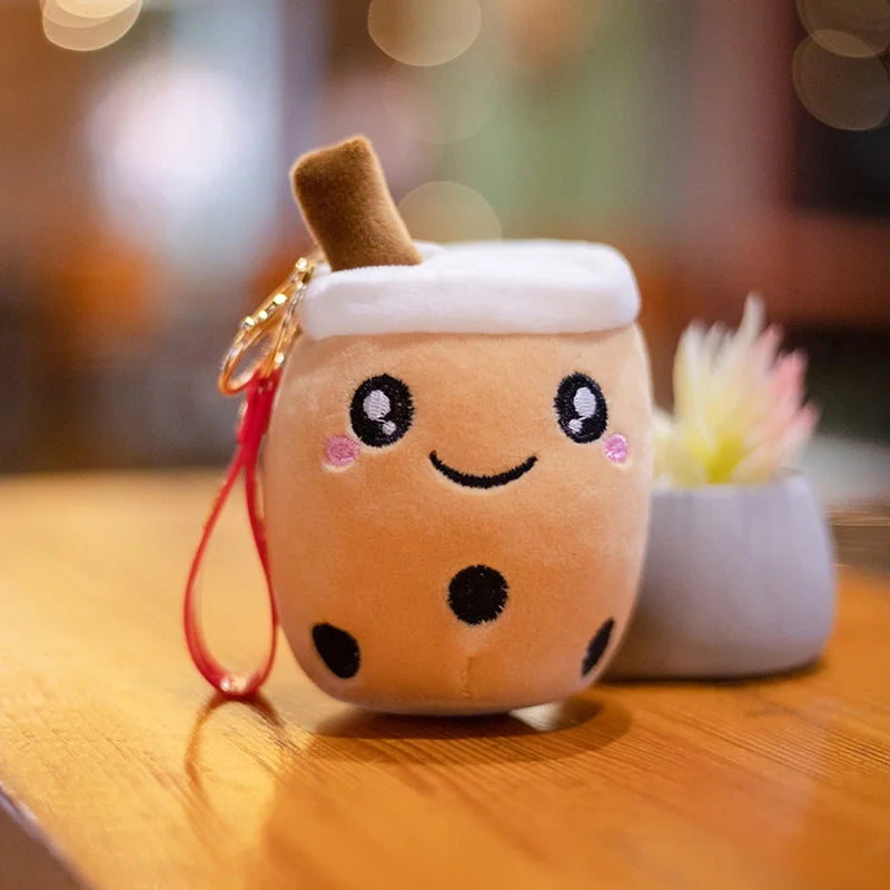 Kawaii plush toy resembling a bubble tea with a keychain on a wooden surface.
