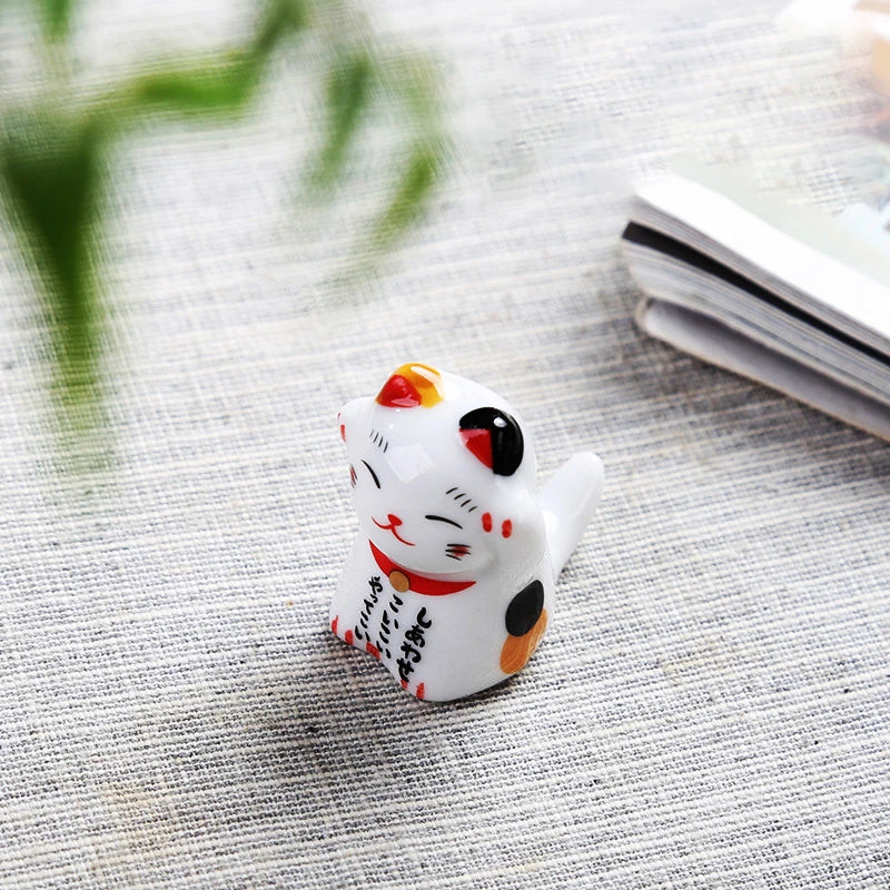 Small white kawaii cat figurine with black spots on a textured surface