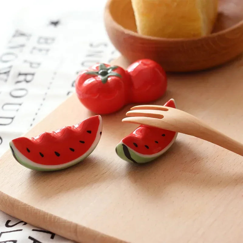 Ceramic kawaii fruit-shaped items including tomatoes and watermelon slices on a wooden surface.