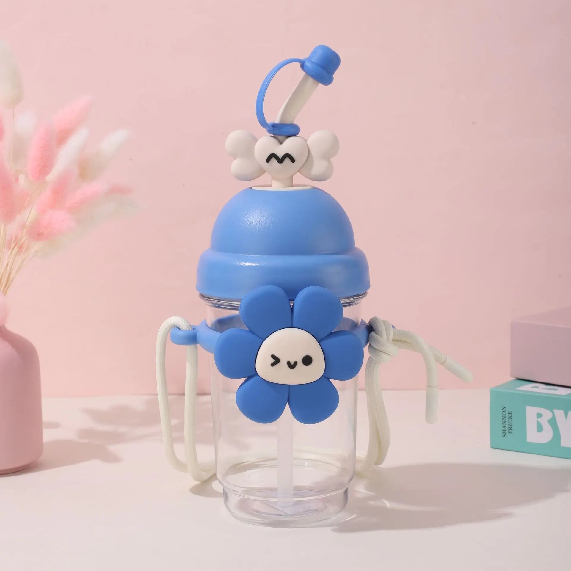 Children's blue water bottle with a Kawaii flower design on a pink background
