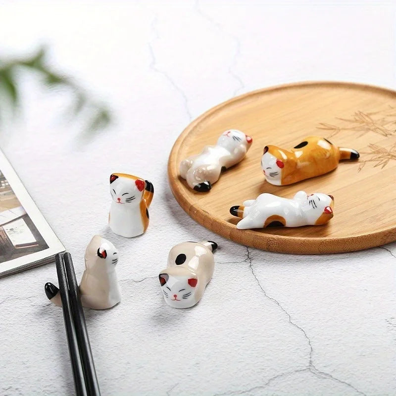 Set of small kawaii ceramic cat figurines on a wooden plate with a blurred background