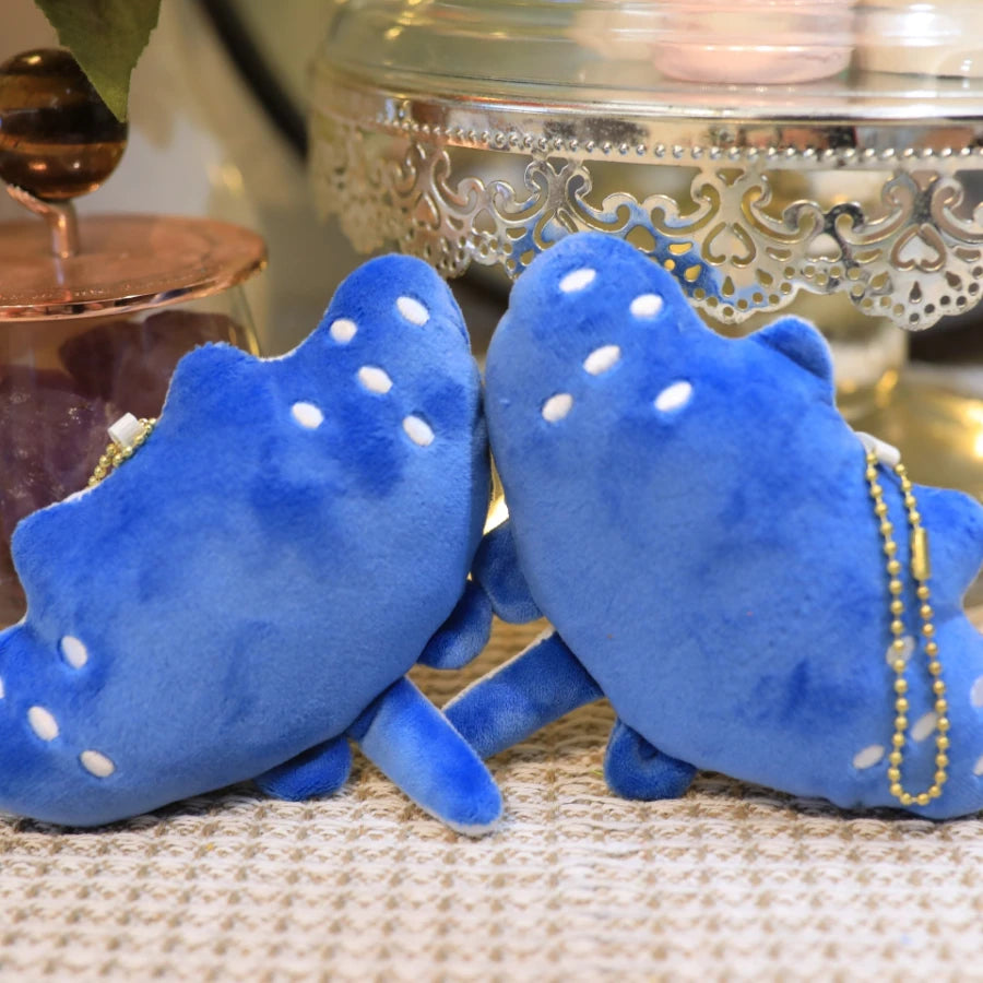 Two blue plush kawaii toys with white polka dots on a textured surface.