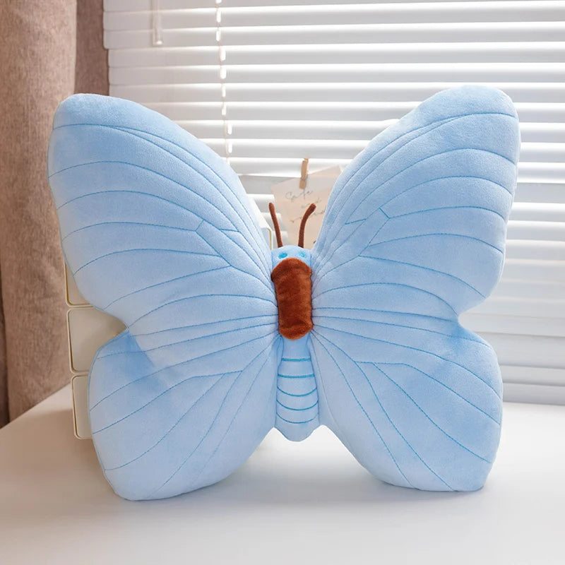 Blue butterfly-shaped kawaii pillow on a surface with a window in the background