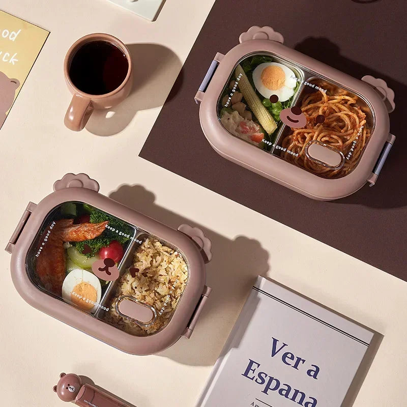 Two kawaii pink bento boxes with food compartments on a table with a mug and book.