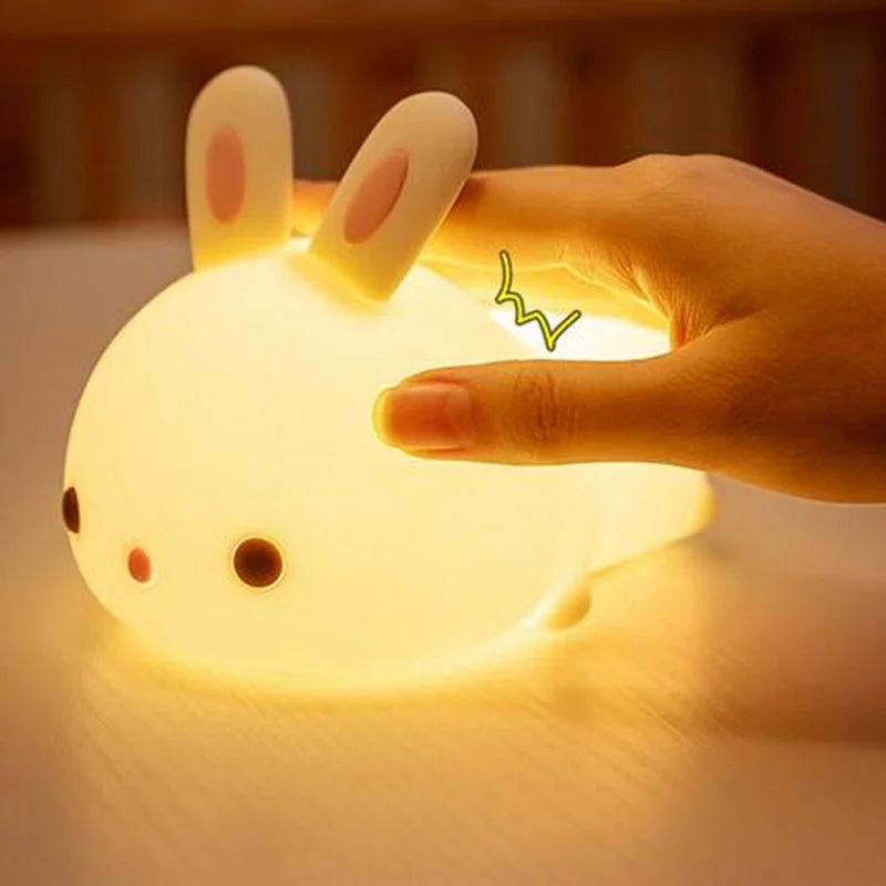 Glowing rabbit-shaped kawaii night light being held by a hand with a blurred background