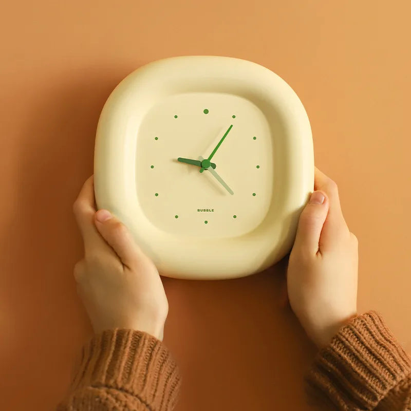 Person holding a square-shaped kawaii clock with a green hand against a warm brown background