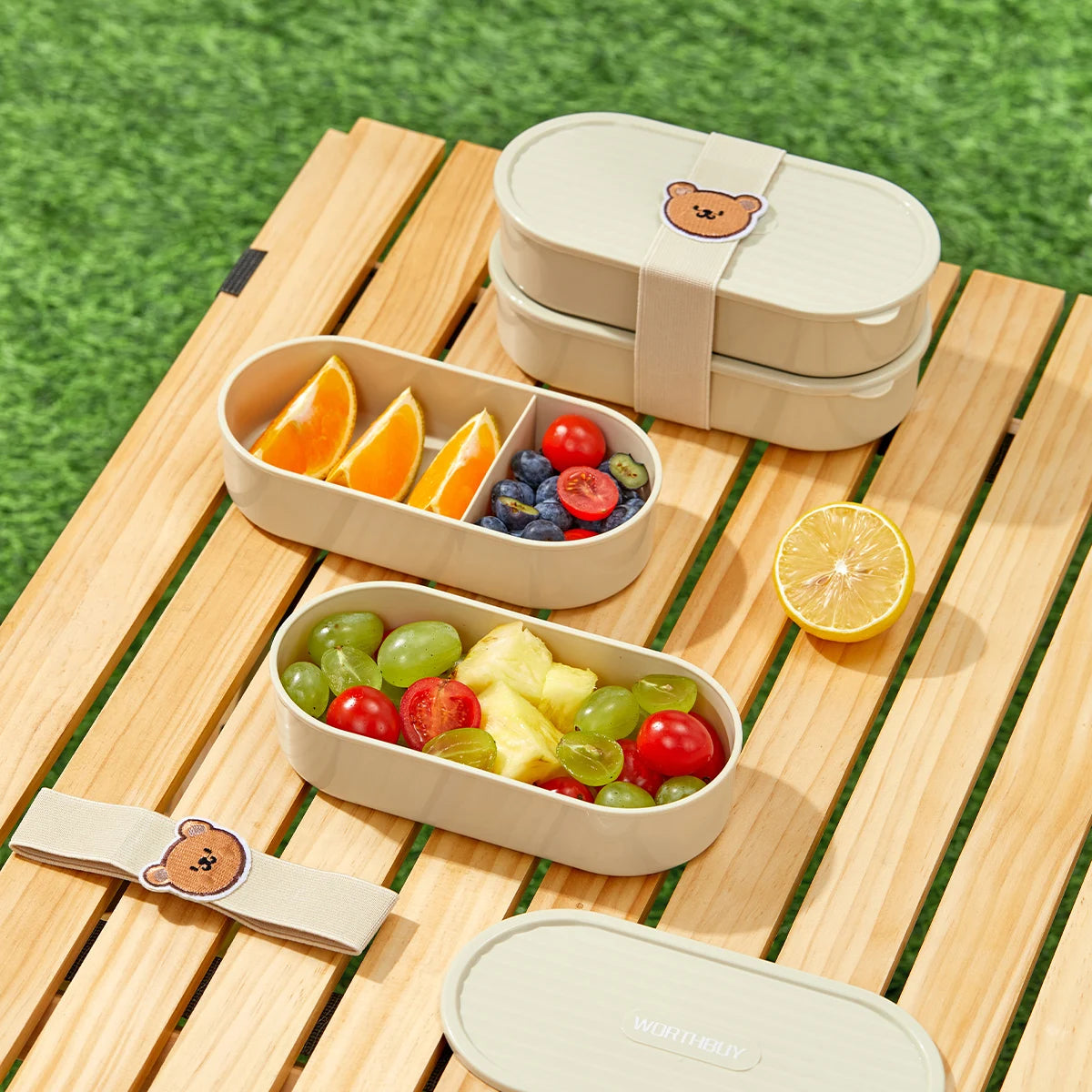 Kawaii beige bento box with compartments filled with fruits on a wooden table outdoors.