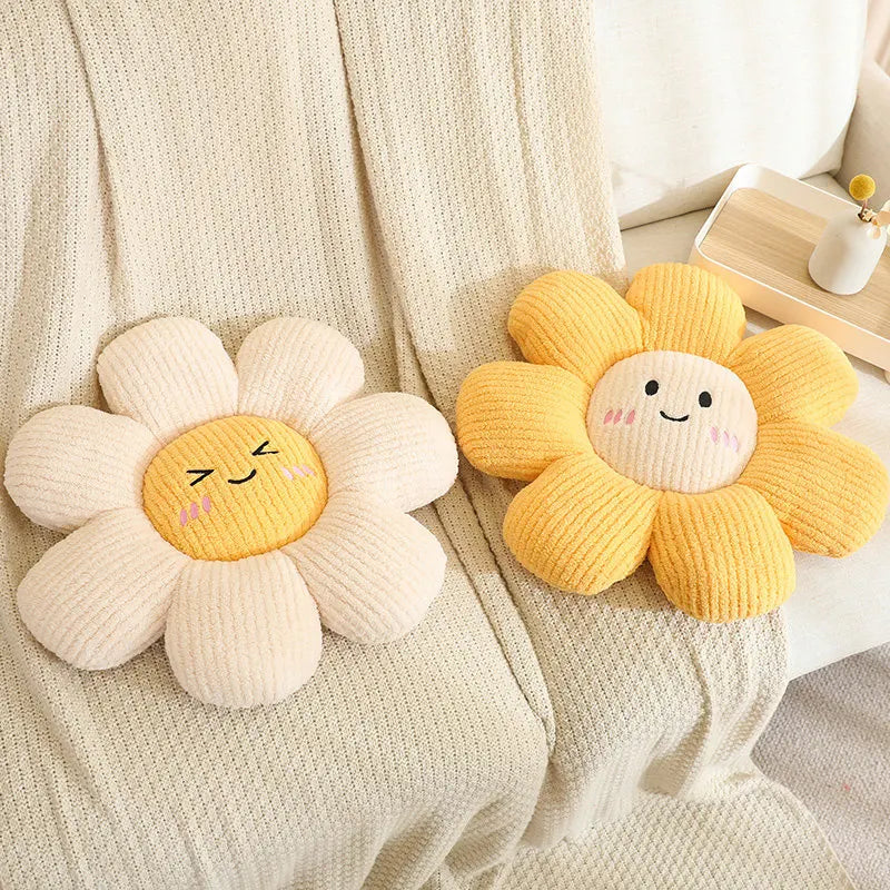 Two knitted flower-shaped kawaii cushions with smiling faces on a soft fabric background.