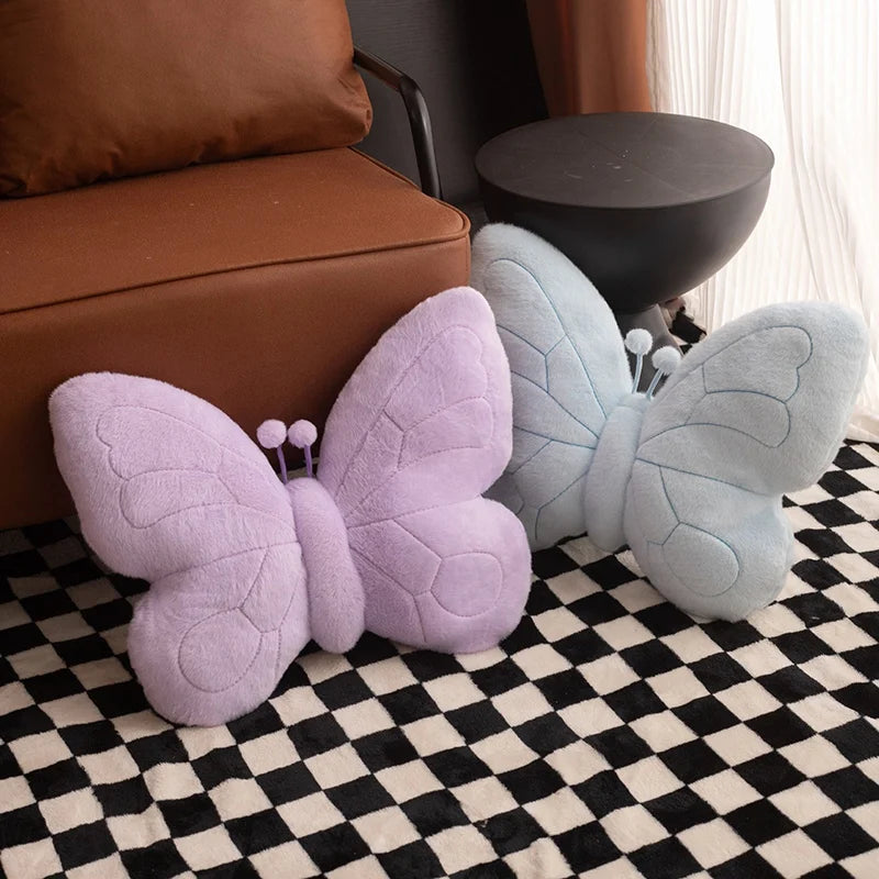 Butterfly-shaped kawaii cushions in purple and gray on a checkered floor.