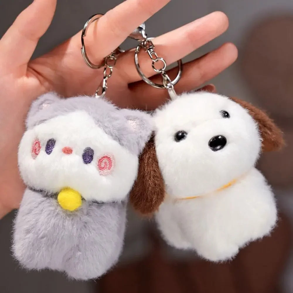 Two kawaii plush keychains, one gray and one white with brown ears, held by a hand.