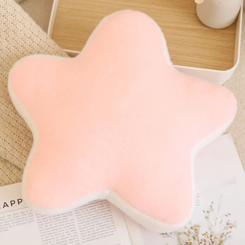 Star-shaped pink kawaii cushion on a surface with a book and candle in the background