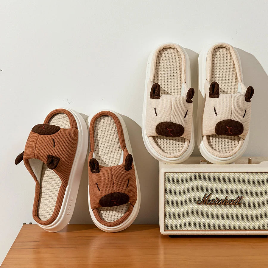 Pair of brown and white slippers with kawaii animal face design next to a Marshall speaker on a wooden surface.