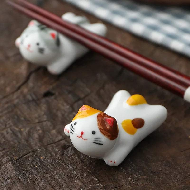 Ceramic kawaii cat-shaped sushi stopper on a wooden surface with chopsticks.