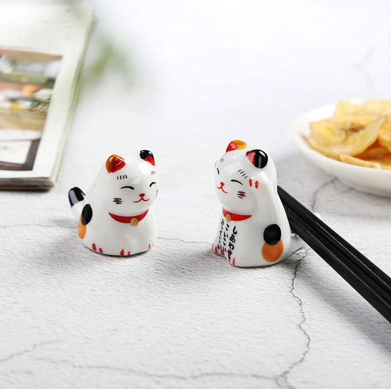 Two ceramic kawaii cat-shaped salt and pepper shakers on a marble surface with chopsticks.