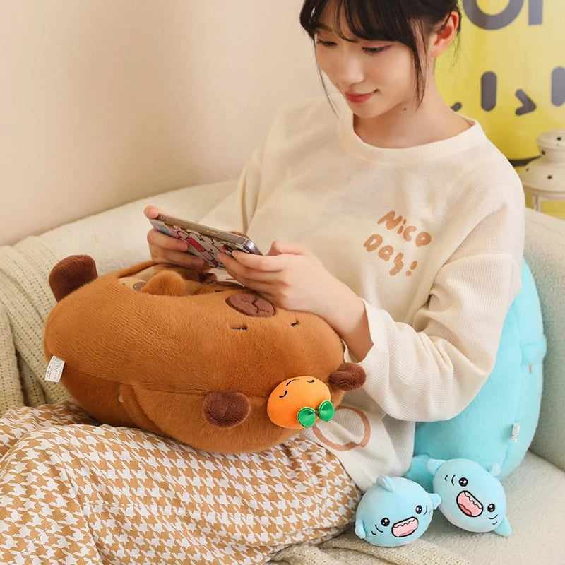 Person sitting on a couch with a brown kawaii plush toy and a blue plush toy, using a phone.