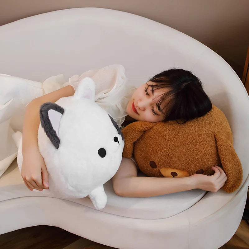 Woman lying on a couch holding a white plush dog kawaii toy and a brown plush bear toy.
