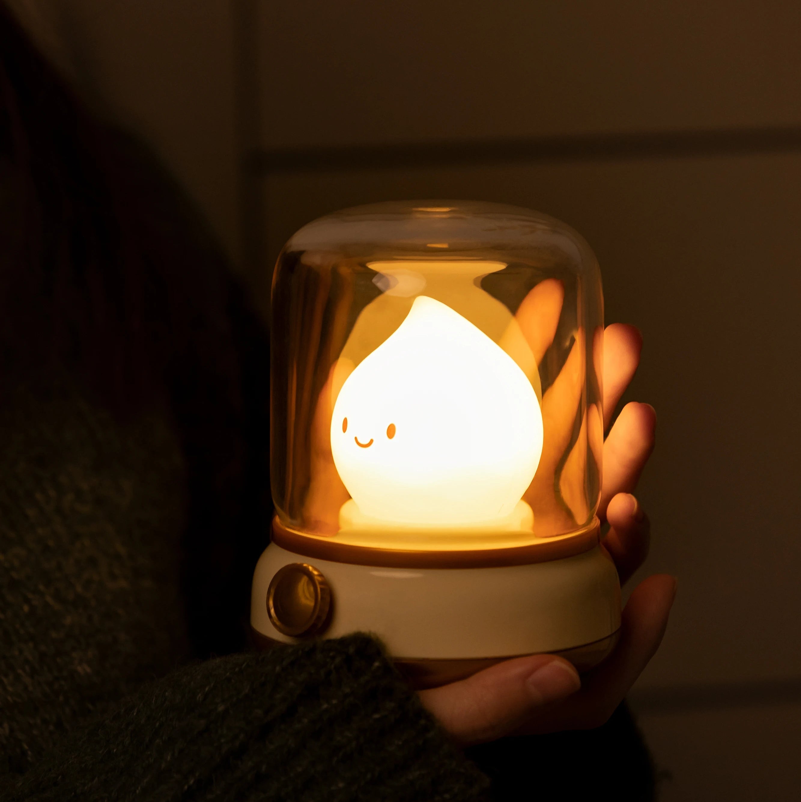 Hand holding a small, glowing kawaii night light with a warm yellow light.