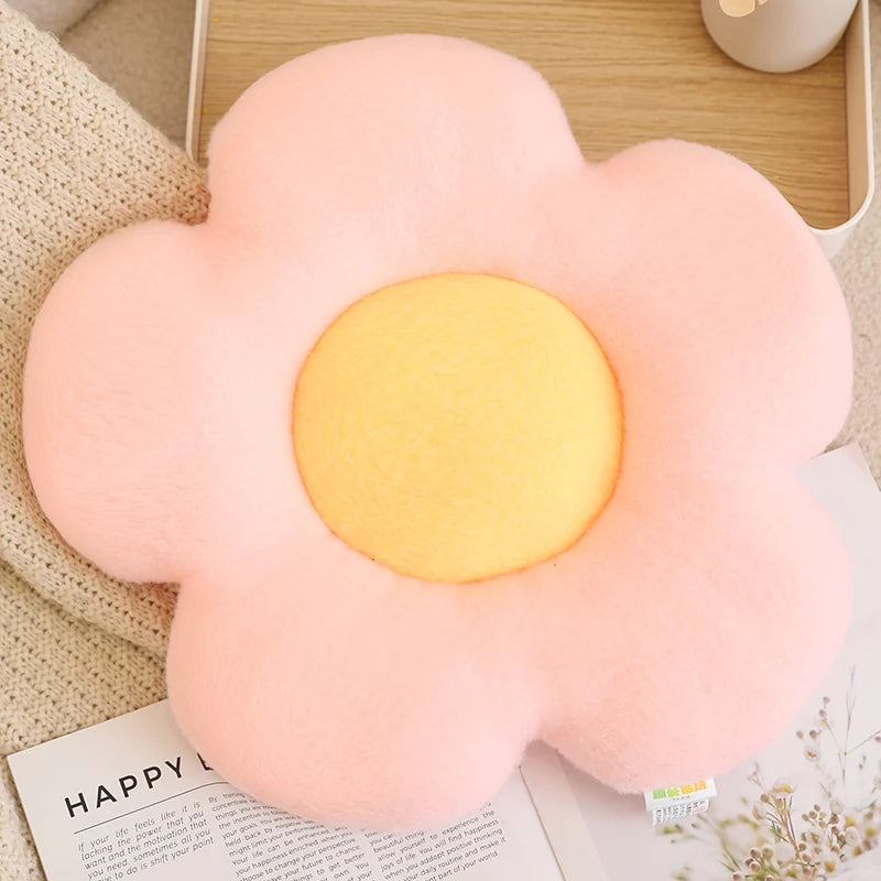 Flower-shaped pink and yellow kawaii cushion on a surface with a magazine underneath.