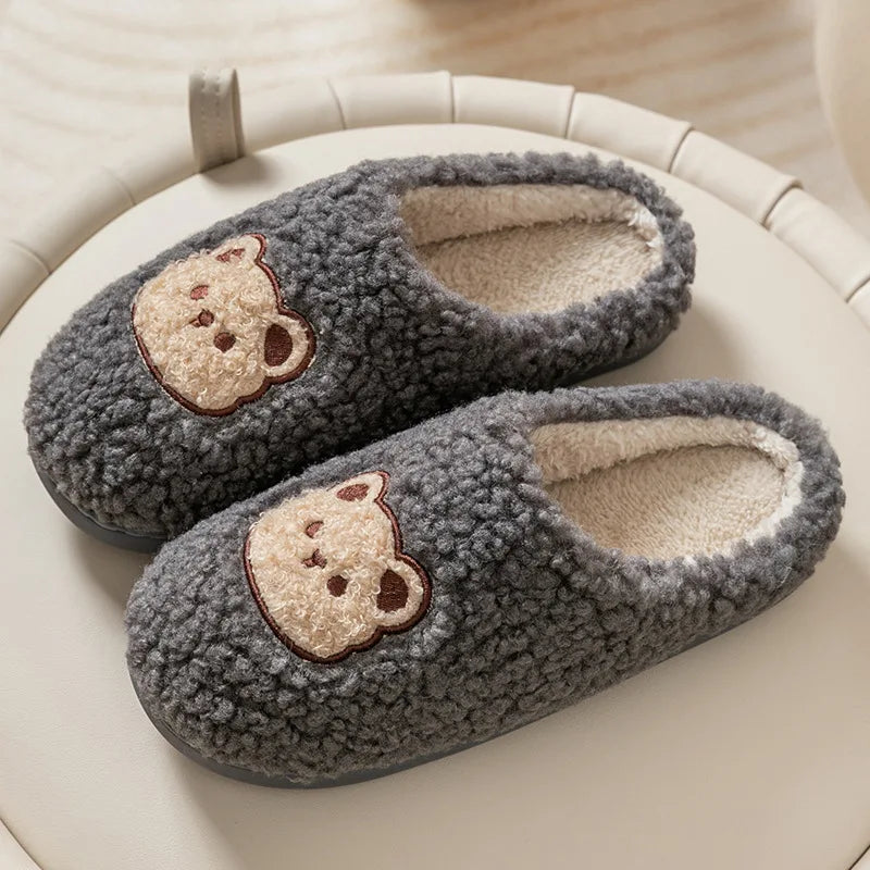 Pair of gray slippers with kawaii bear face designs on a beige surface