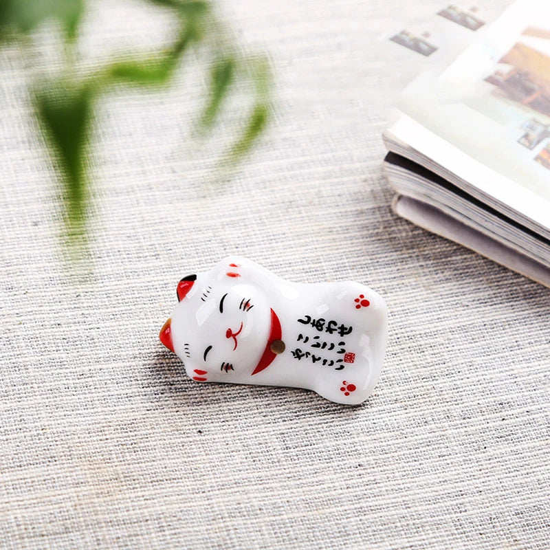 Small white kawaii cat figurine with red accents on a textured surface