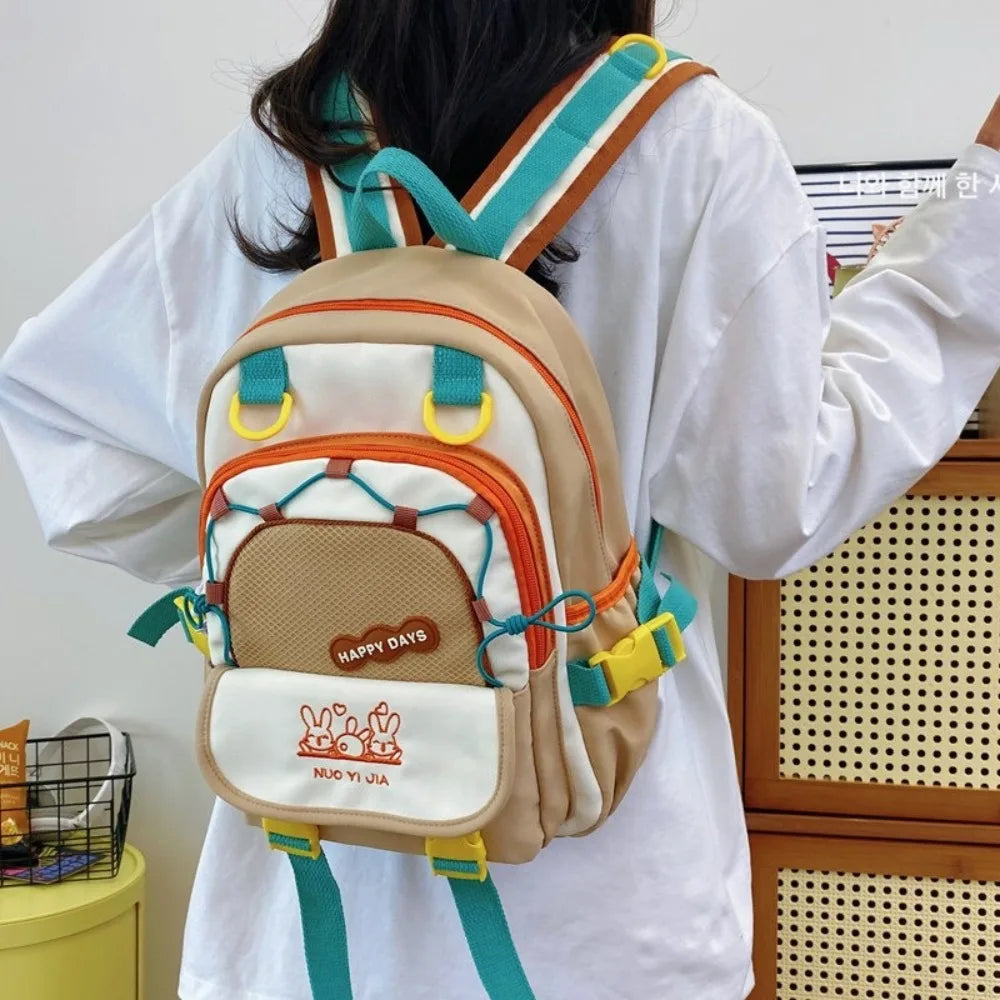 Person wearing a Kawaii colorful backpack with 'Happy Days' and 'Nico Yi Ola' branding.