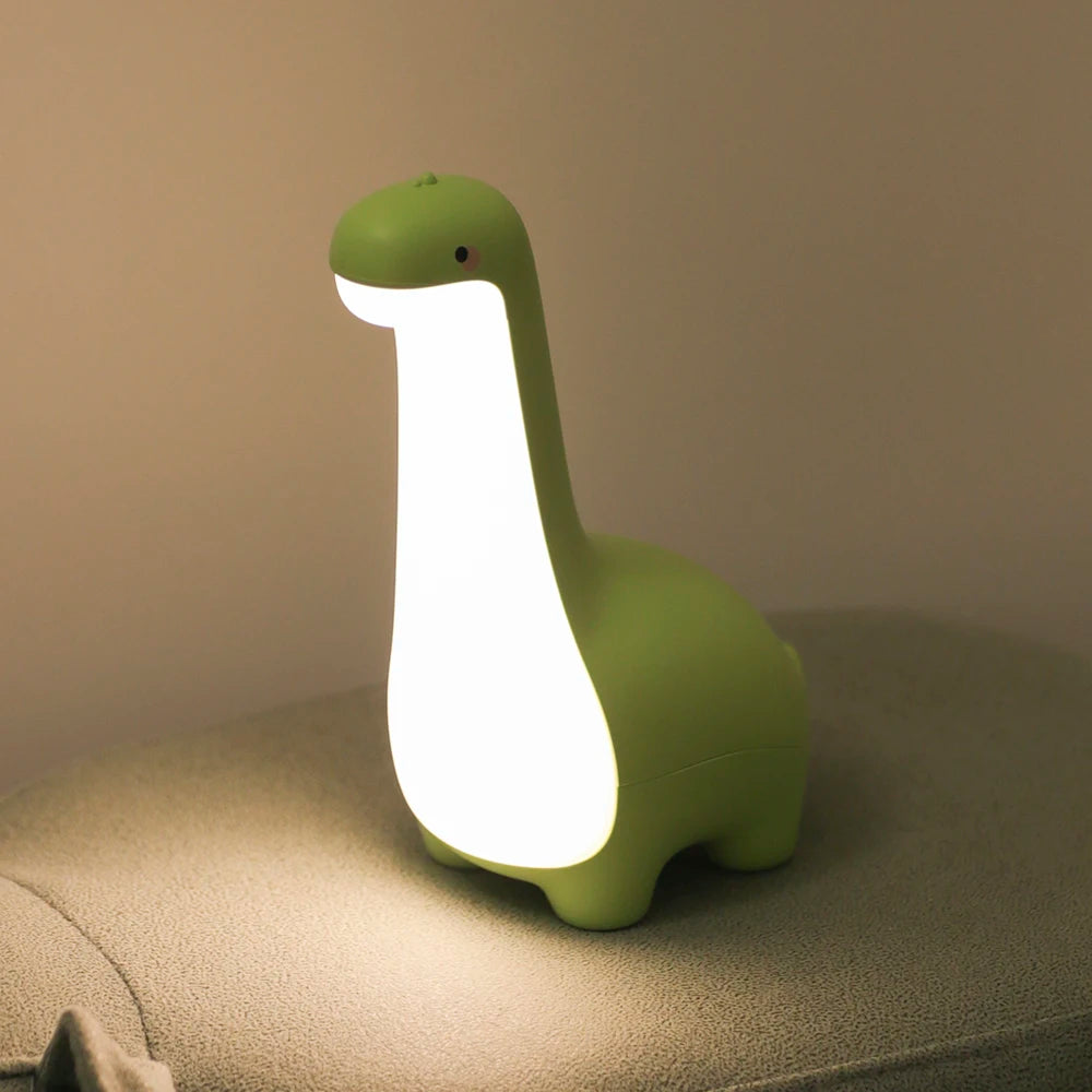 Green dinosaur-shaped kawaii night light on a surface with a neutral background
