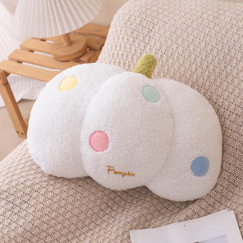 Plush pumpkin kawaii pillow with colorful spots on a beige couch