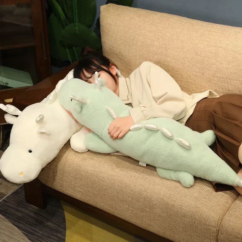 Person lying on a couch holding a large green plush toy, with another kawaii plush toy partially visible.