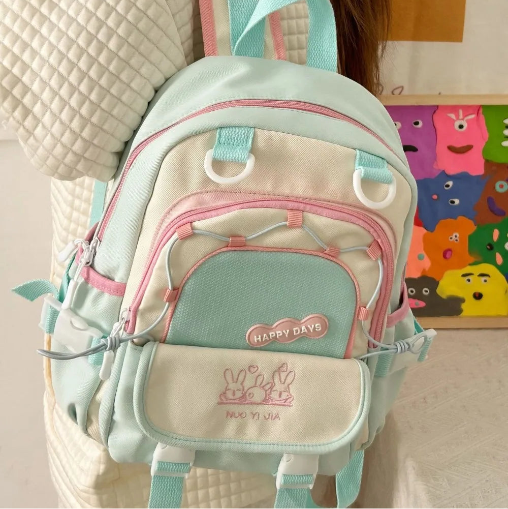 Pastel-colored Kawaii backpack with pink and blue straps worn by a person, with a colorful wall in the background.