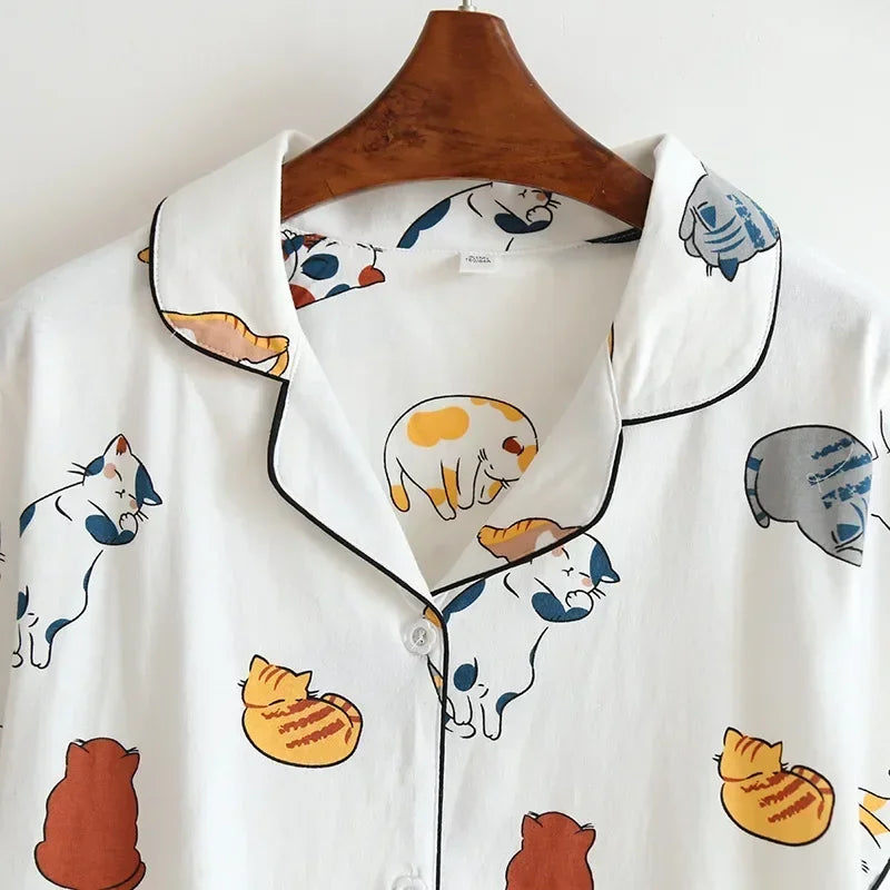 White shirt with kawaii cat pattern on a wooden hanger against a white background