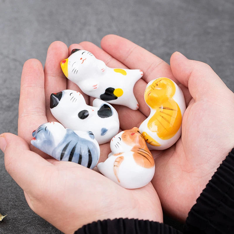 Small kawaii cat figurines held in a hand against a gray background